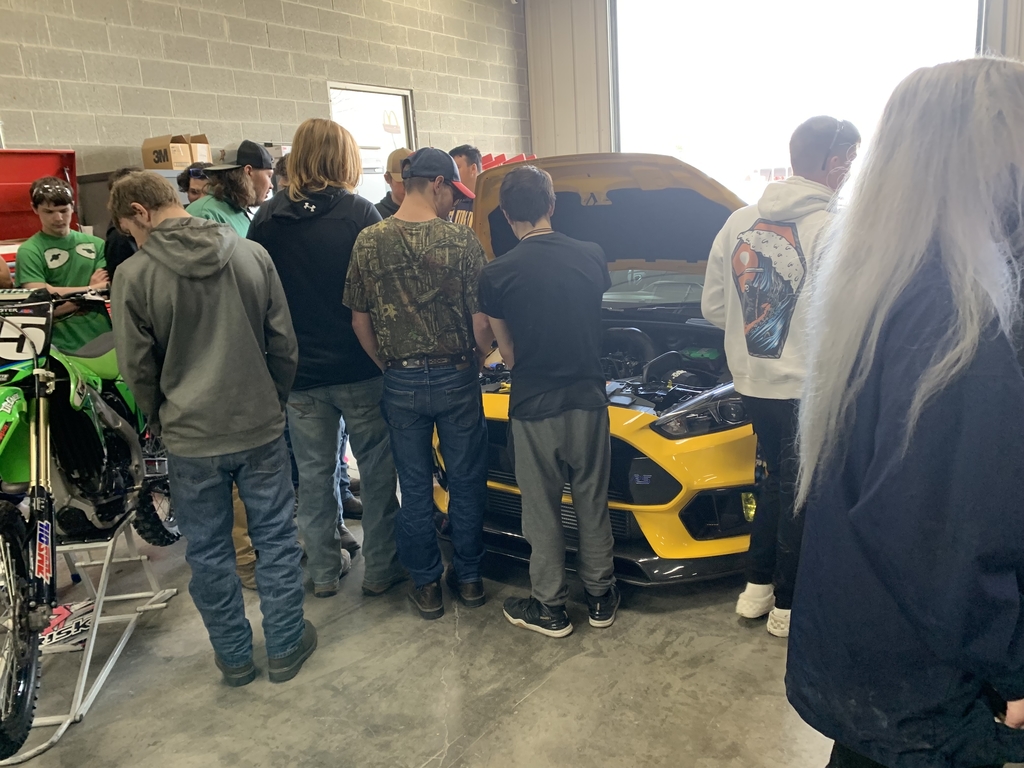 students looking at yellow car